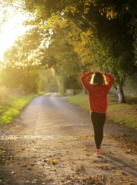 A woman going on a nature walk with the sun setting in the distance