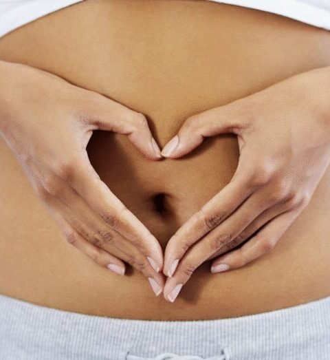 Woman forming a heart over her abdomen to represent a healthy gut