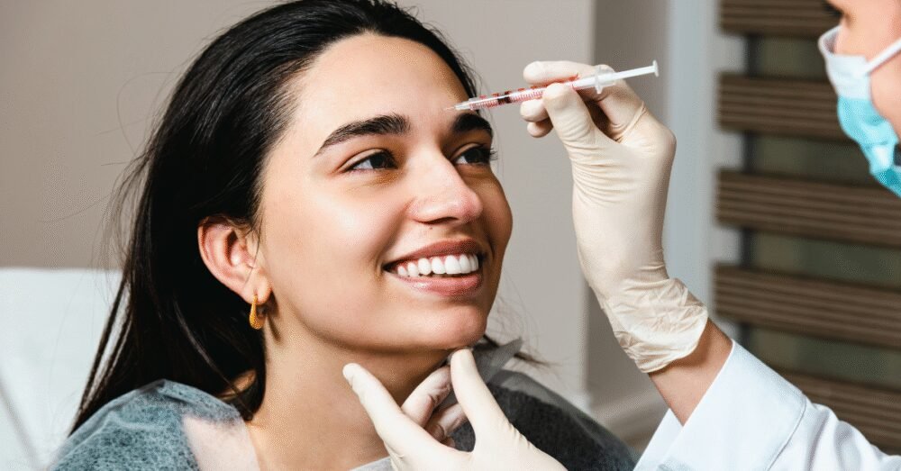 Woman receiving injections between her brows from a gloved practitioner