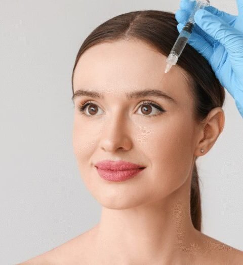 Woman receiving Botox injections above her brow area from a gloved provider